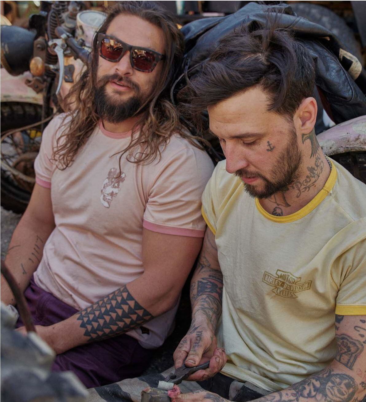 Jason Momoa and a face-tattooed friend showing off the pastel ringer T-shirts from the collection.