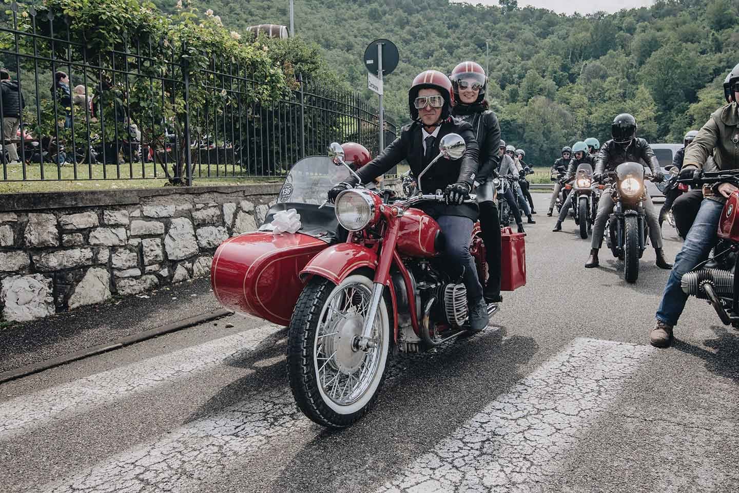 An Italian rider (and distinguished gentleman) with lady pillion rider and unidentified sidecar passenger, Brescia, Italy.